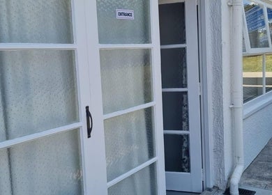 Entrance to Reiya Thai Massage in Auckland, NZ featuring elegant white doors and peaceful surroundings.