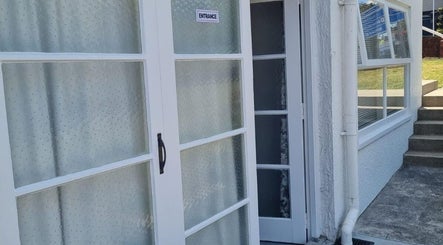 Entrance to Reiya Thai Massage in Auckland, NZ featuring elegant white doors and peaceful surroundings.
