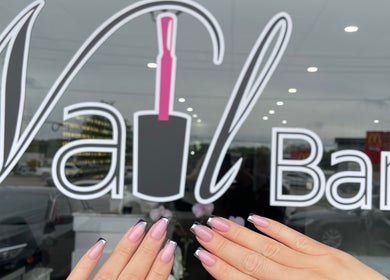 Stylish manicure at The Nail Bar, Oshawa, Ontario, CA with elegant nail art in front of the venue logo.