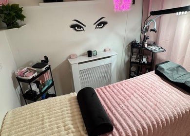 Cozy beauty room at Lashed By Xio, London, England, GB with pink decor and a treatment bed.