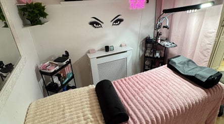 Cozy beauty room at Lashed By Xio, London, England, GB with pink decor and a treatment bed.