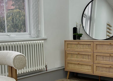 Elegant interior at Mika Beauty, Wilmslow, England, featuring a mirror and woven wood dresser.