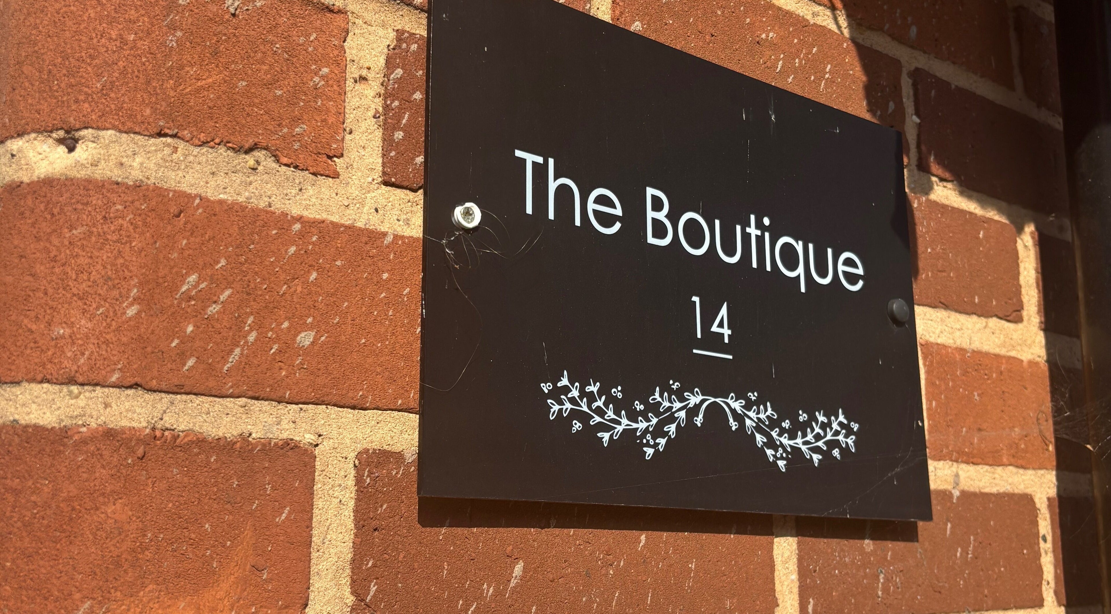 Brick wall with boutique sign outside Hair By Hope, Knowle, England, GB. Stylish entrance decor.