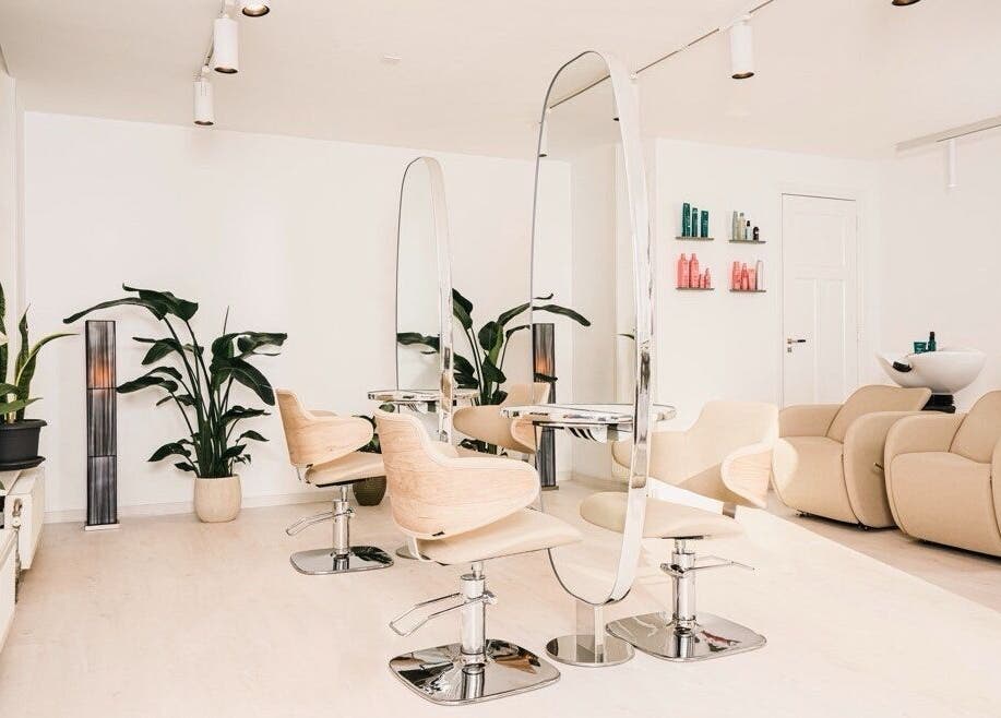 Modern salon interior at Shah Saatchi, Amsterdam, Noord-Holland, NL featuring sleek chairs and lush plants.