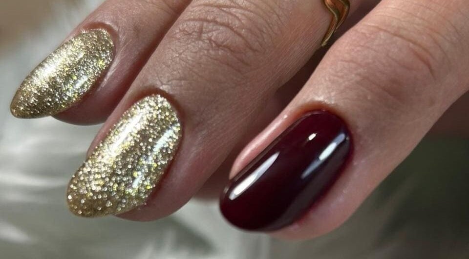 Diseño de uñas elegantes con brillo dorado y rojo en Denmnails, Maipú, Región Metropolitana, CL.