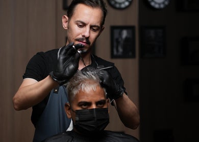 Stylist at Prepare Yourself Salon in Al Hofuf, Eastern Province, SA, skillfully cutting a client's hair.
