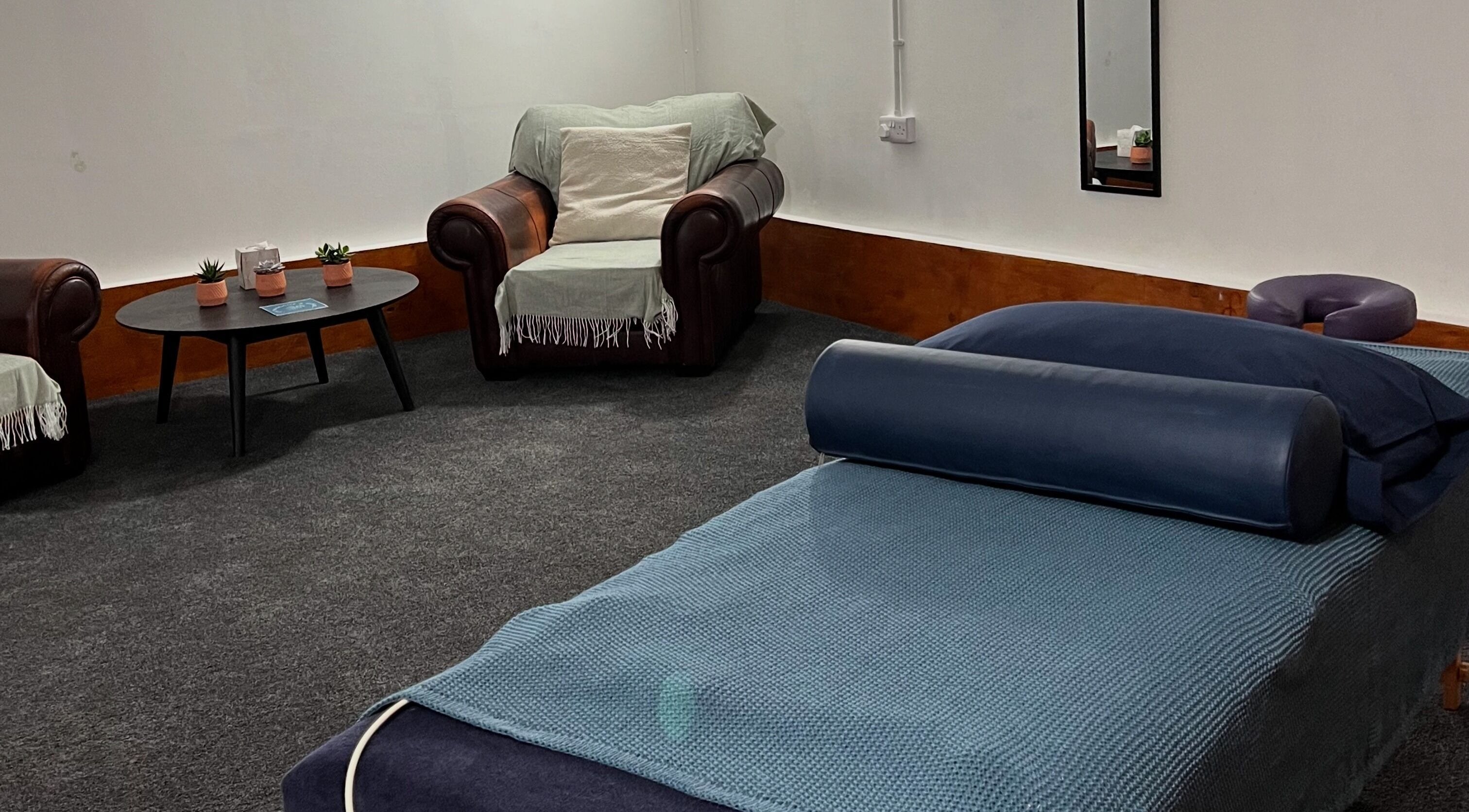 Relaxing therapy room at CH Massage & Rehab, Poltimore, England, GB, with a cozy chair and massage table.