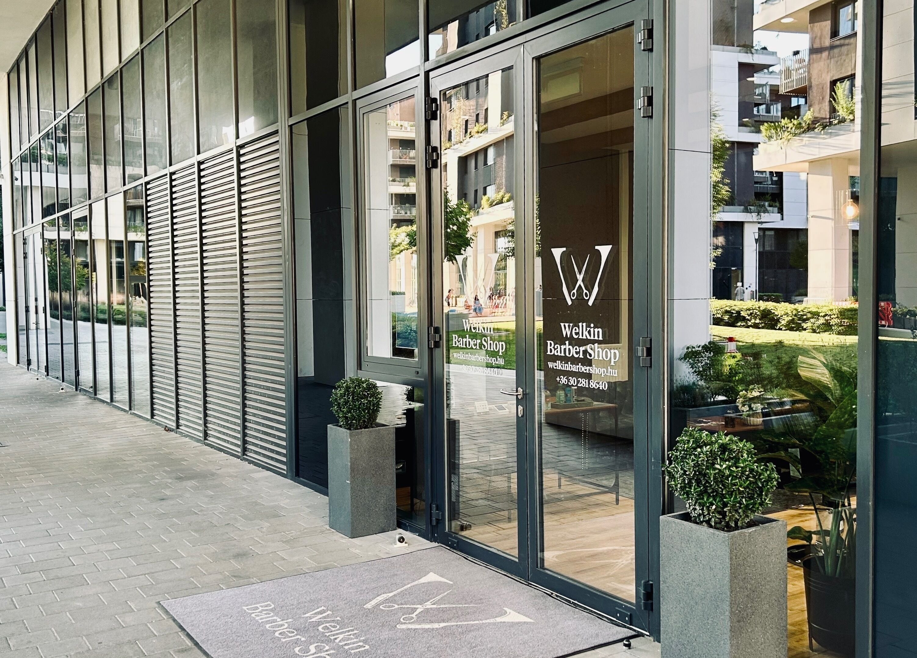 Welkin Barber Shop bejárata Budapesten, Magyarország, elegáns üvegajtókkal.