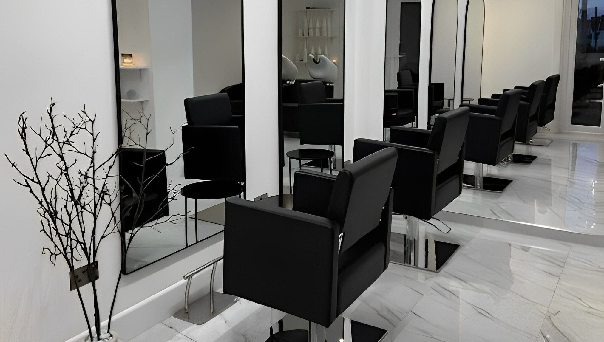 Elegant salon setup at STUDIO HONEY, Southampton, England, GB featuring sleek black chairs and large mirrors.