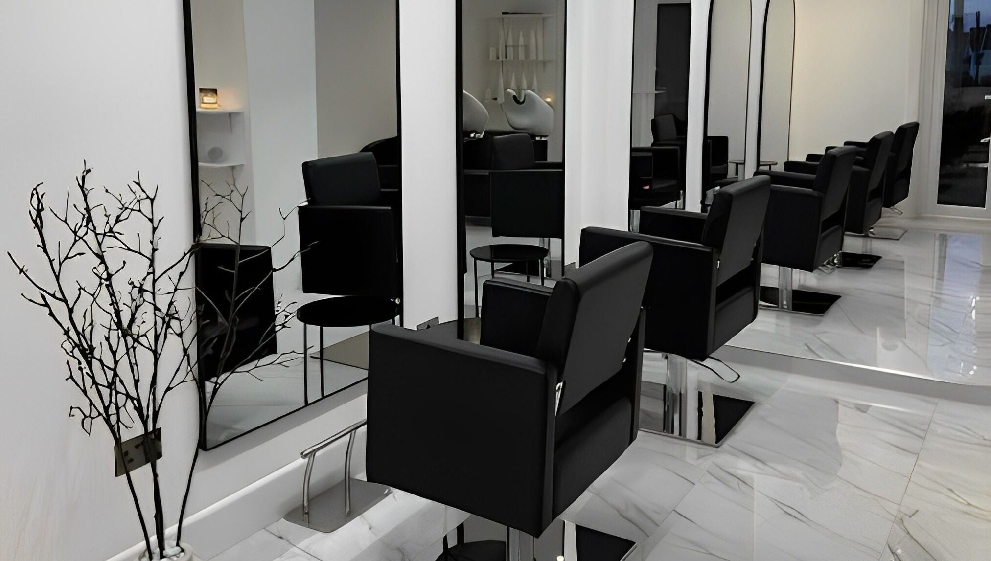 Elegant salon setup at STUDIO HONEY, Southampton, England, GB featuring sleek black chairs and large mirrors.