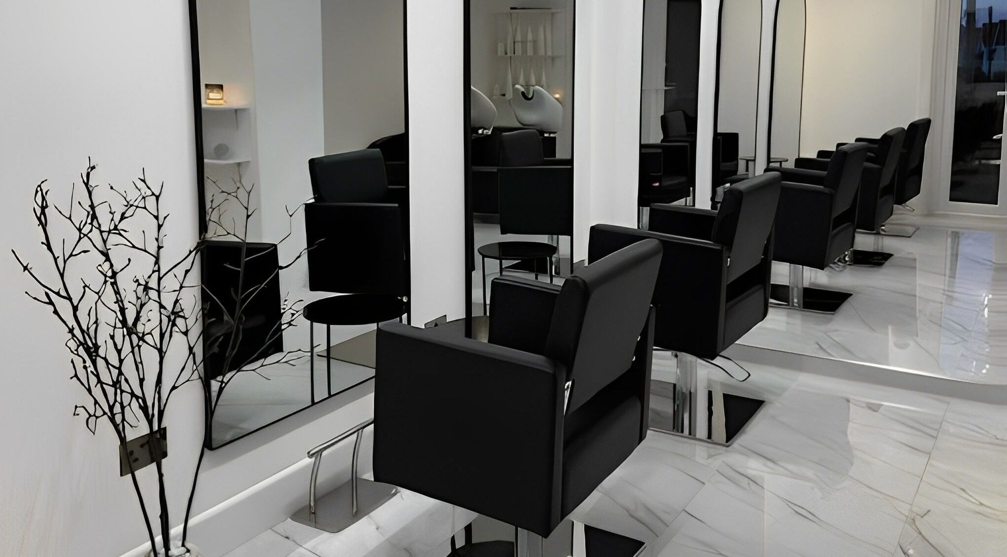 Elegant salon setup at STUDIO HONEY, Southampton, England, GB featuring sleek black chairs and large mirrors.