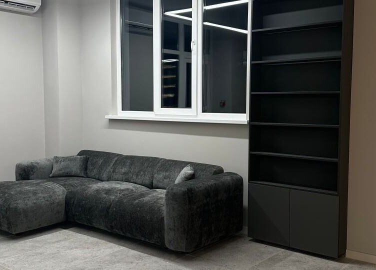 Modern lounge area at Barber&Co in Chișinău with a dark gray sofa and sleek black bookshelf.