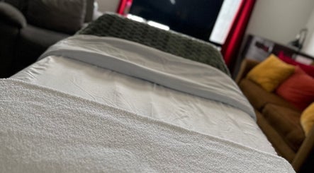 A cozy massage bed in Skintimacy Wellness and Esthetics, Phoenix, Arizona, US, with plush pillows and soft lighting.