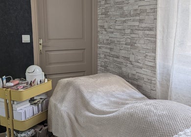 Salle de soins paisible à Vénuseum, Mouy, Hauts-de-France, FR, avec lit confortable et chariot de beauté.