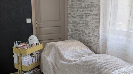 Salle de soins paisible à Vénuseum, Mouy, Hauts-de-France, FR, avec lit confortable et chariot de beauté.
