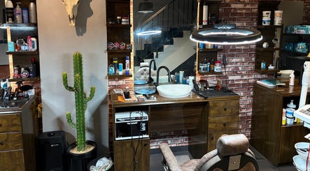 داخل صالون ذا دارك سِزر | The Dark Scissor Barber في ينبع، وهو مزين بصبار وديكور حجري.