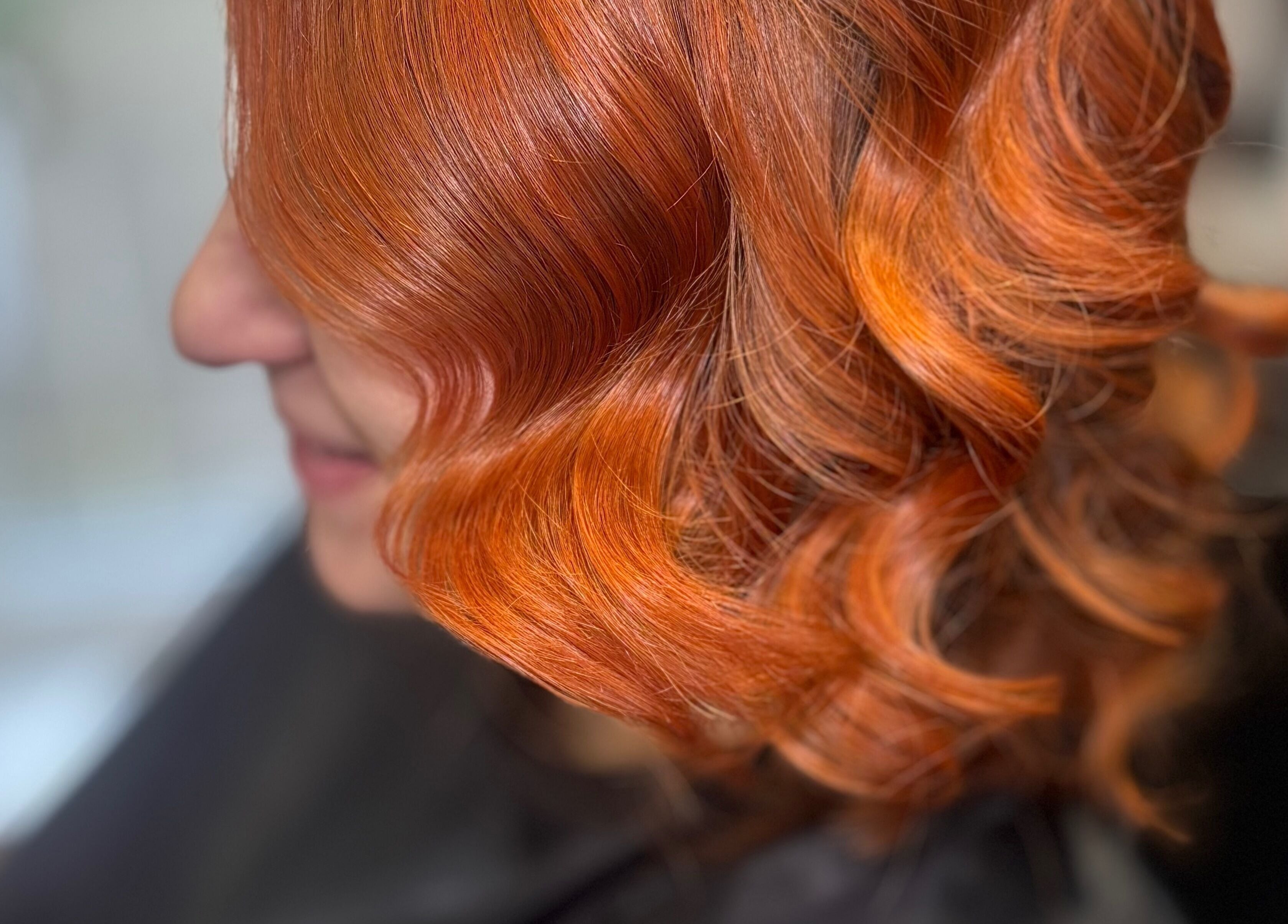 Vibrant red hair styled in curls at Hideaway Hair and Beauty, Llandeilo, Wales, GB, showcasing salon's expertise.