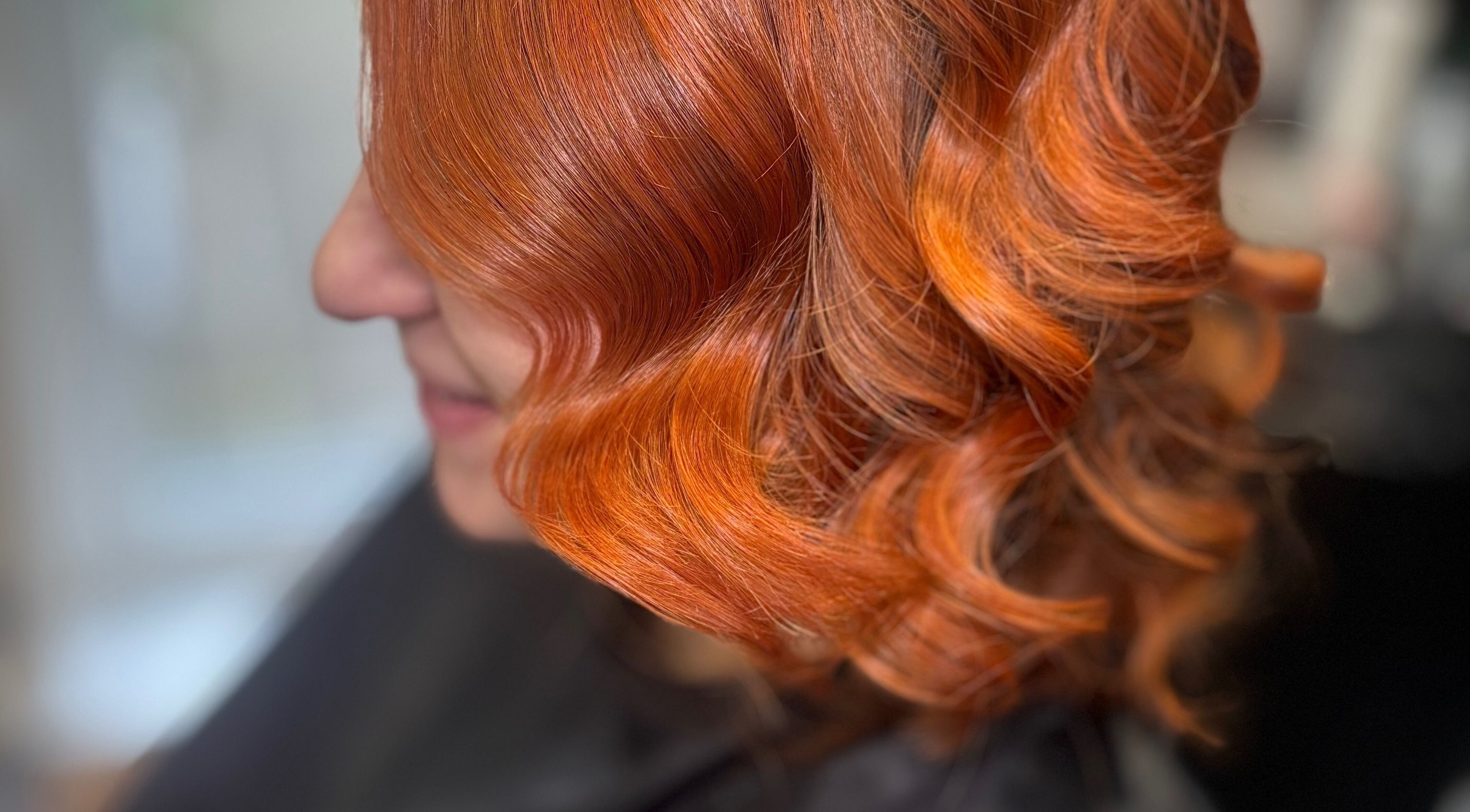 Vibrant red hair styled in curls at Hideaway Hair and Beauty, Llandeilo, Wales, GB, showcasing salon's expertise.