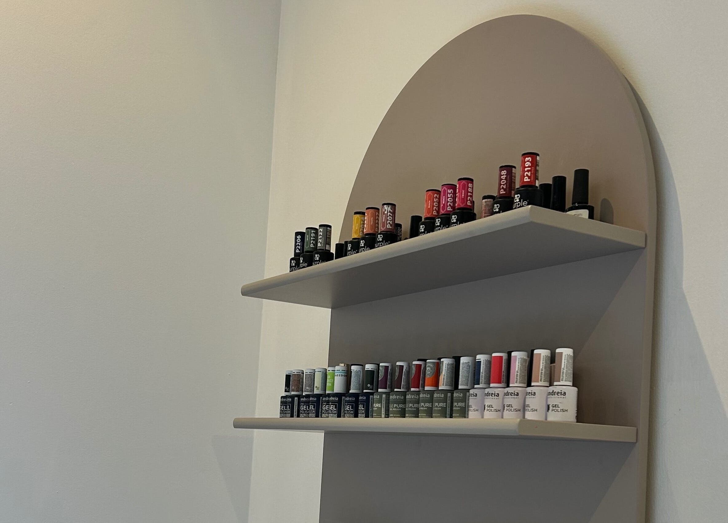 Expositor de esmaltes na Taissa Gomes Nails, Leiria, PT, com variadas cores vibrantes.