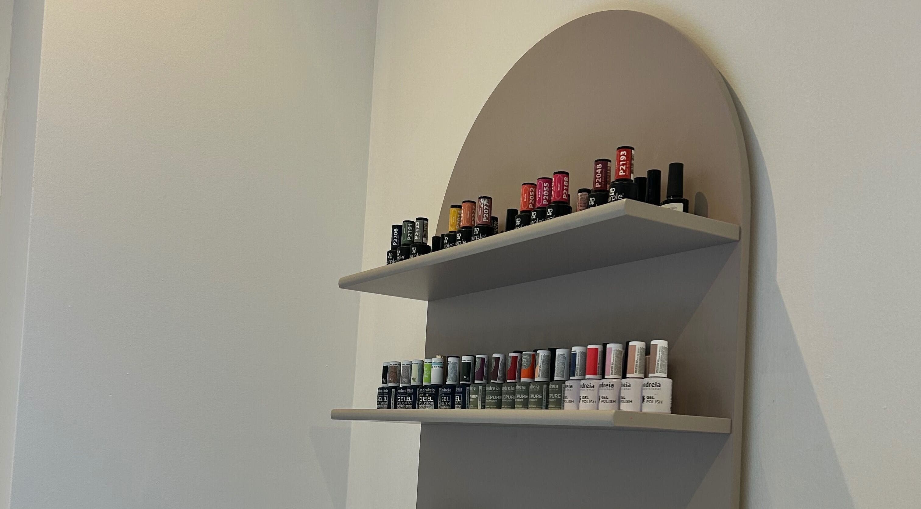 Expositor de esmaltes na Taissa Gomes Nails, Leiria, PT, com variadas cores vibrantes.