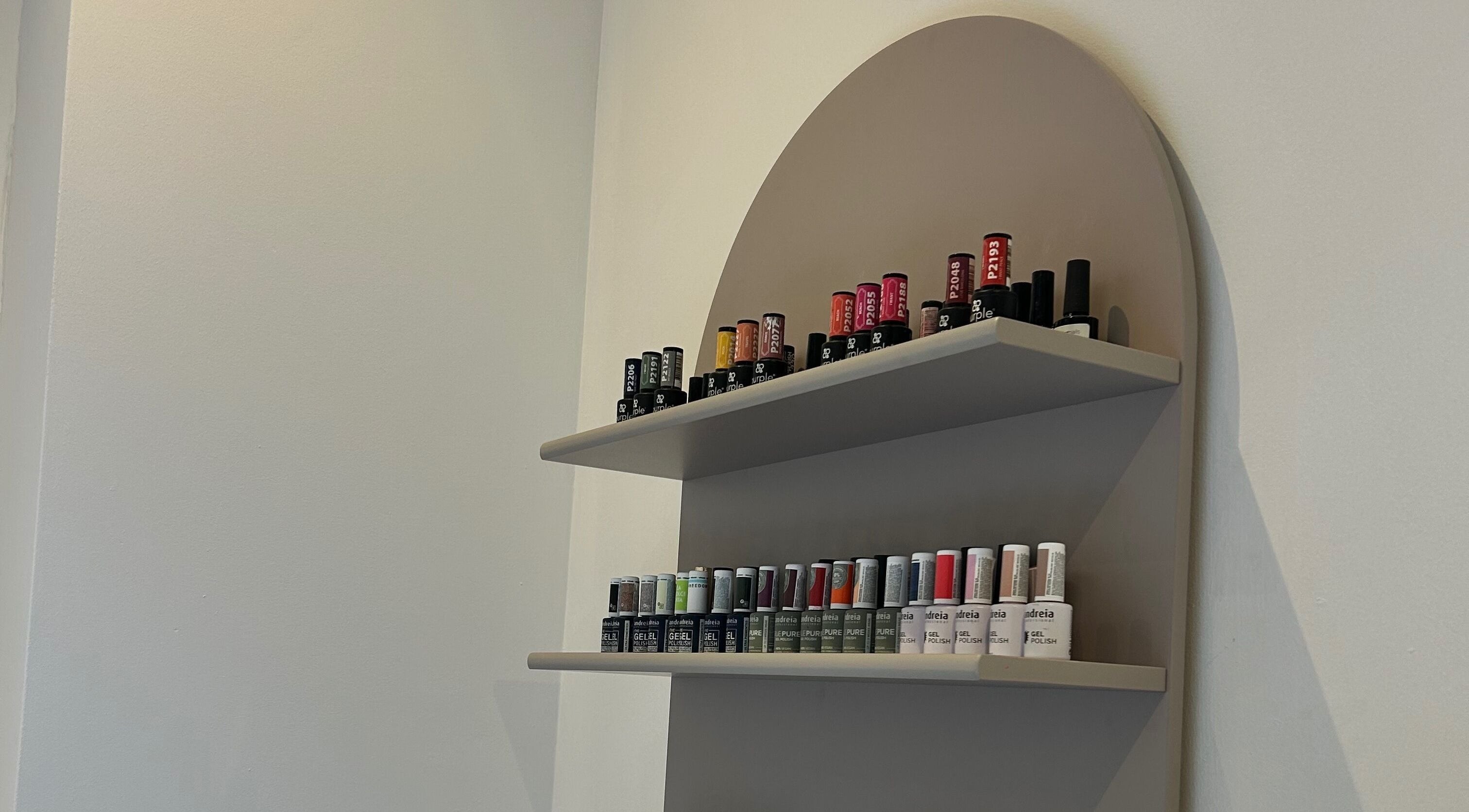 Expositor de esmaltes na Taissa Gomes Nails, Leiria, PT, com variadas cores vibrantes.