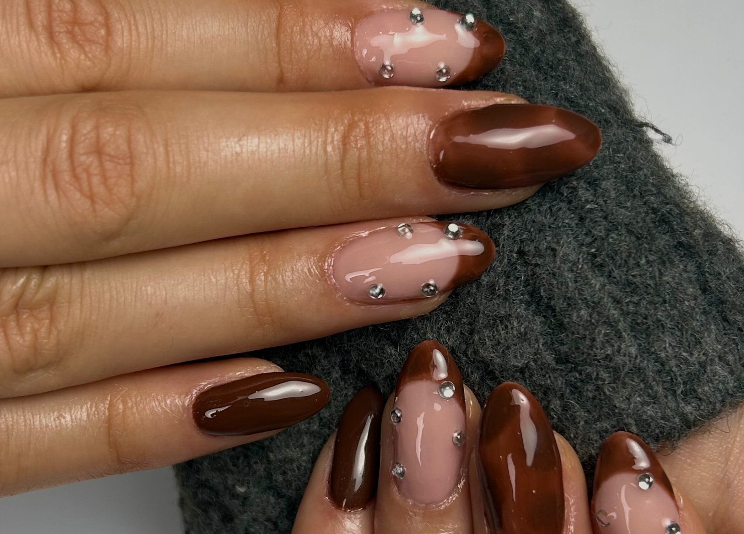 Unhas com esmalte marrom e detalhes de glitter em Taissa Gomes Nails, Leiria, Leiria, PT.