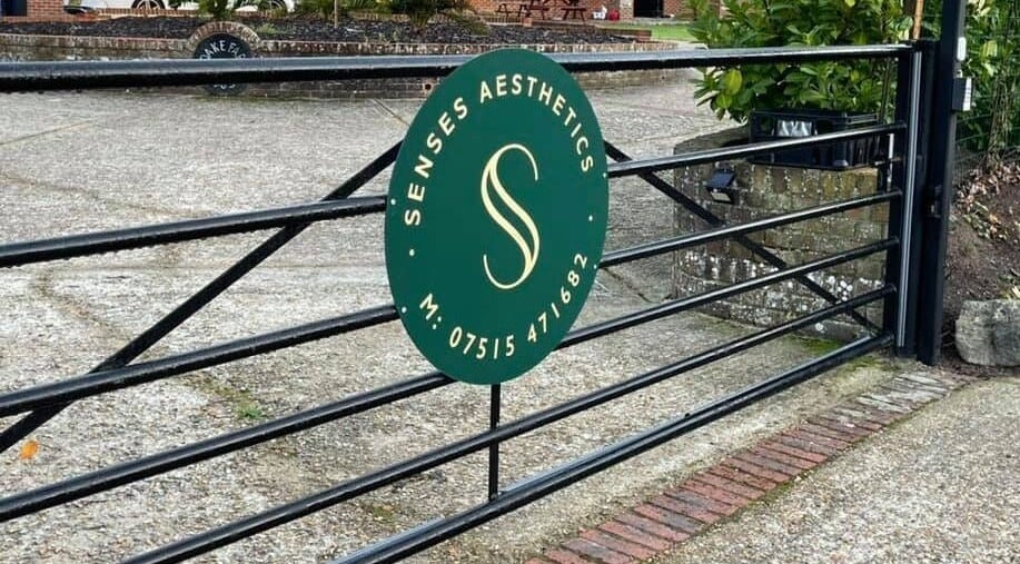 Entrance gate of Senses Aesthetics in Denmead, England, GB with a decorative sign.