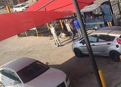 Parking area with red shade and people at Polished by Sarina, Sandton, Gauteng, ZA.