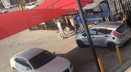 Parking area with red shade and people at Polished by Sarina, Sandton, Gauteng, ZA.
