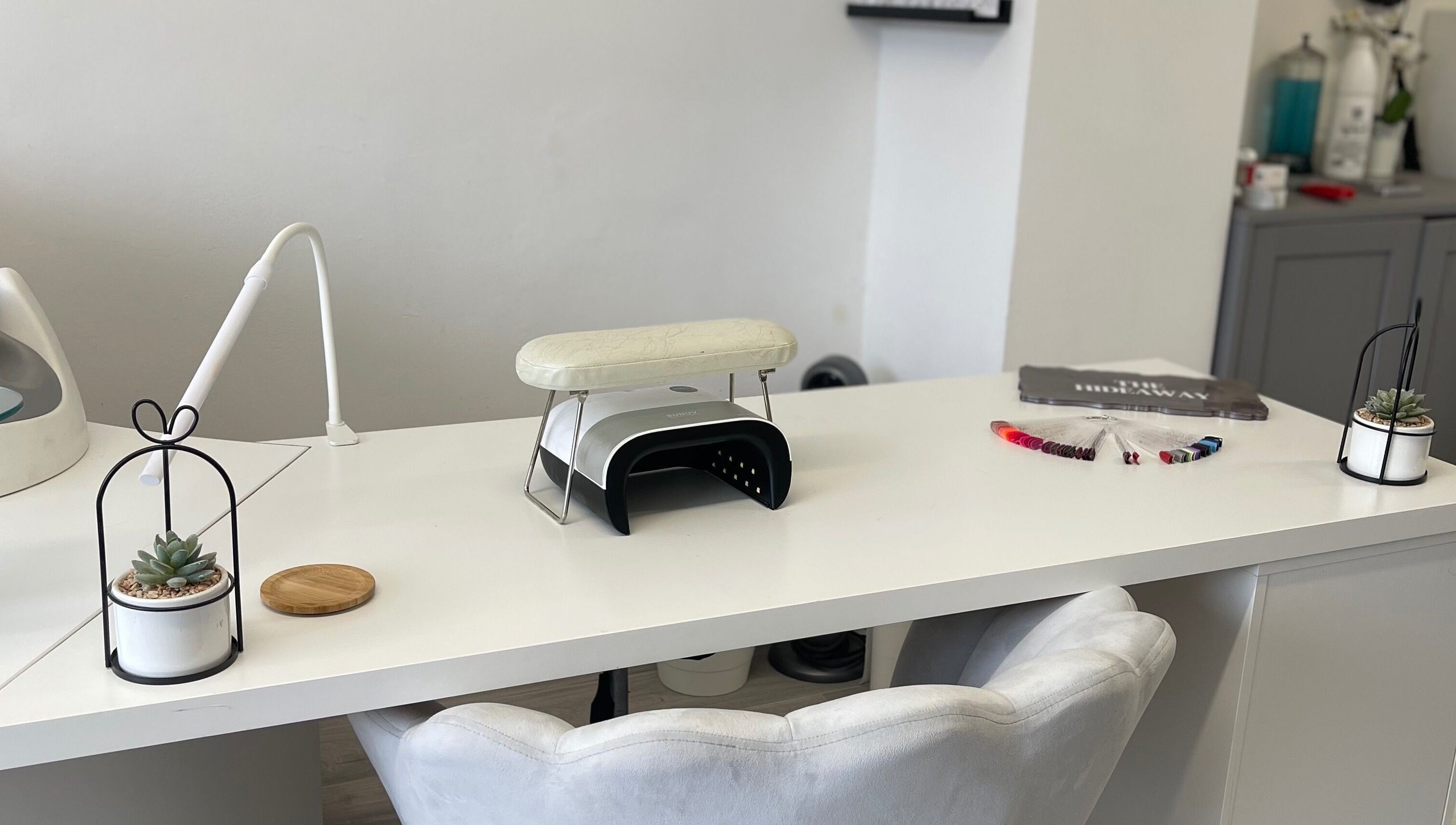 Sleek white nail station at The Hideaway Salon, Malvern, England, GB, with modern decor and manicure tools.