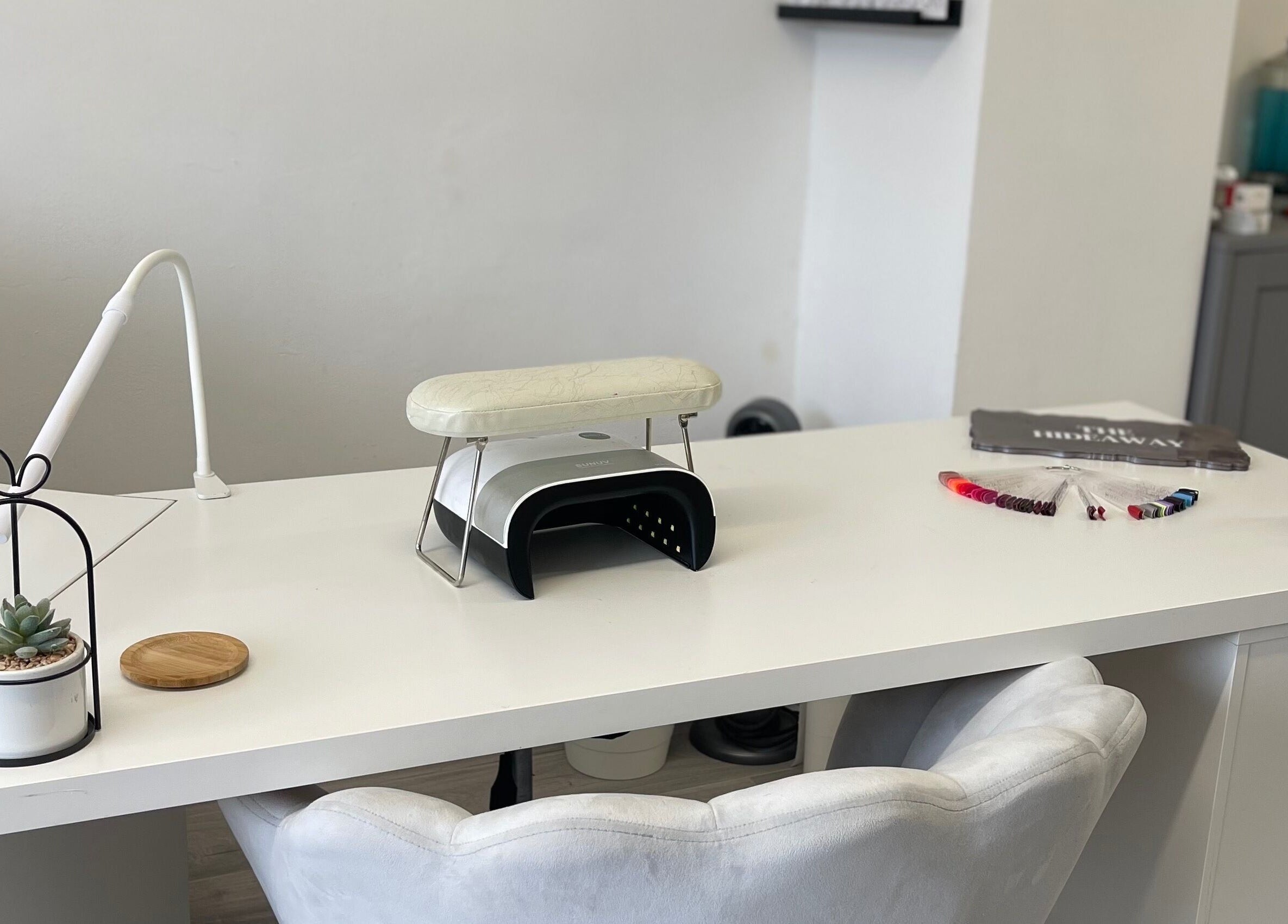 Sleek white nail station at The Hideaway Salon, Malvern, England, GB, with modern decor and manicure tools.