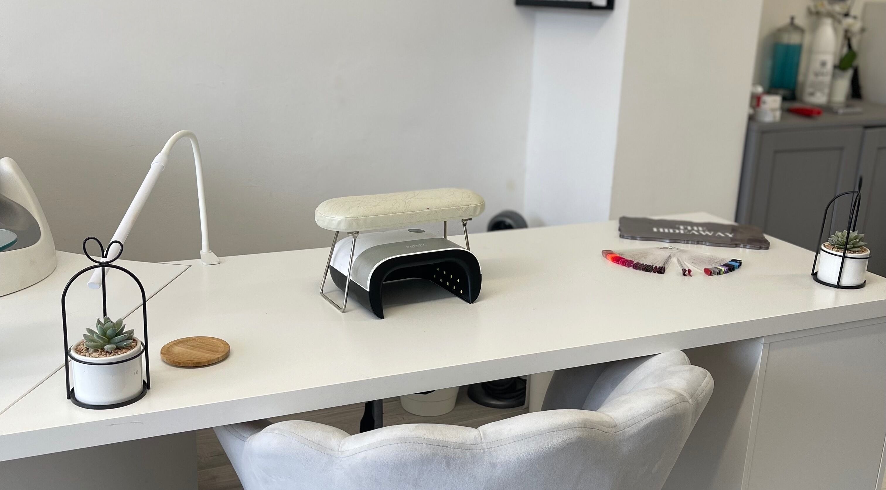 Sleek white nail station at The Hideaway Salon, Malvern, England, GB, with modern decor and manicure tools.