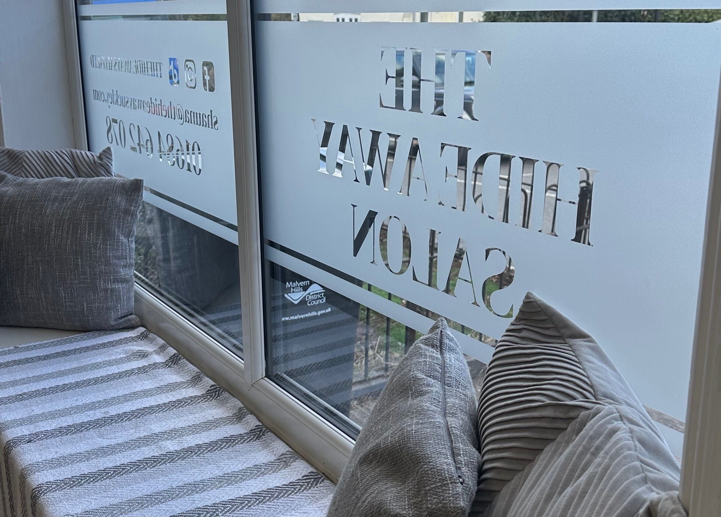 Inviting window seating area at The Hideaway Salon, Malvern, England, GB with plush cushions.