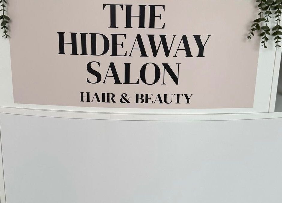 Signage of The Hideaway Salon, a hair and beauty venue in Malvern, England, GB, featuring elegant greenery.