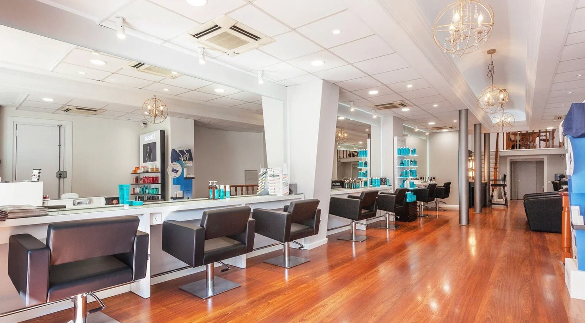 Salón moderno de Hair Cut Day Aragó en Barcelona, Catalunya, ES, con sillas negras y estantes de productos.