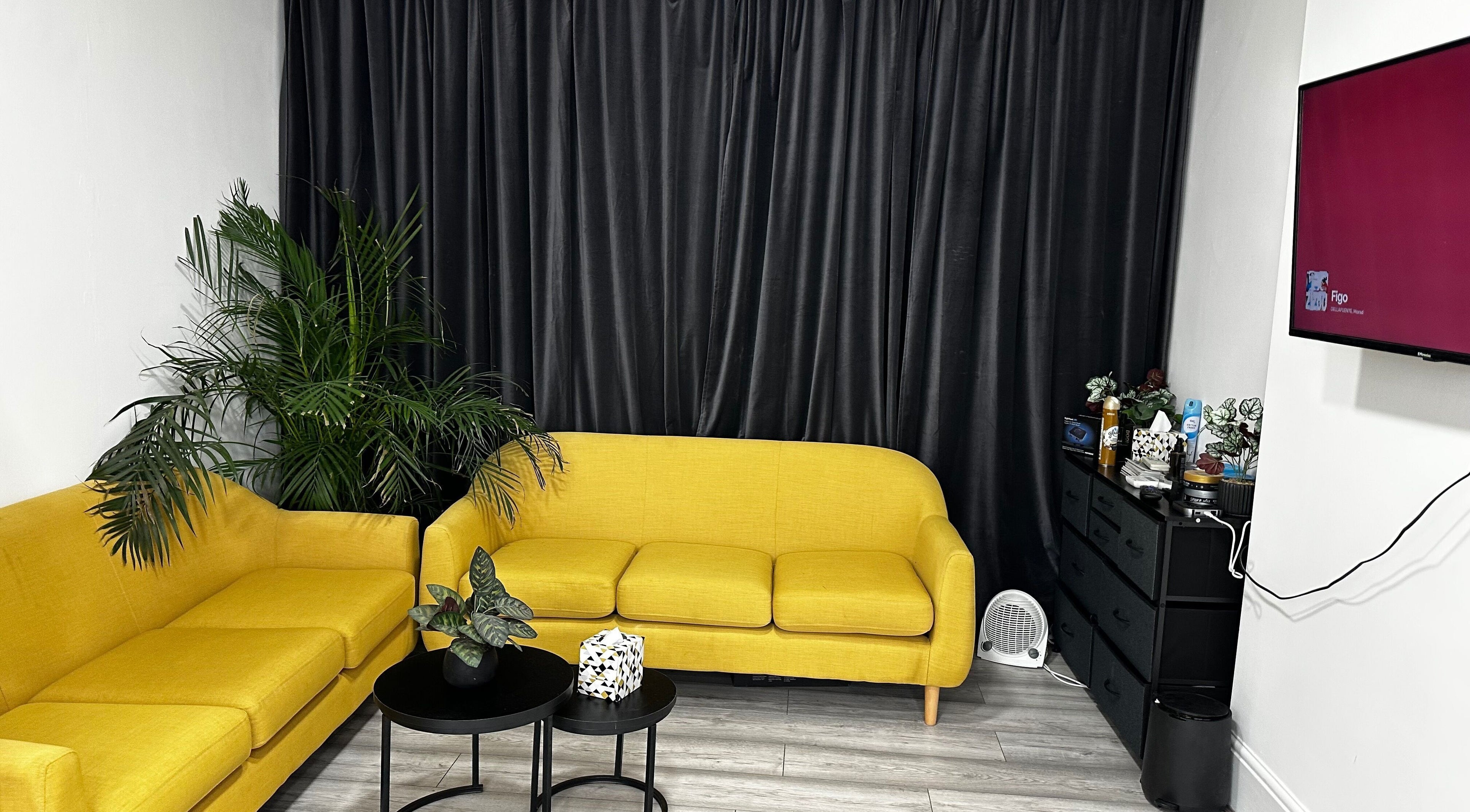 Modern lounge area with yellow sofas at Aries Salon Academy, London, England, GB. Stylish and relaxing venue space.