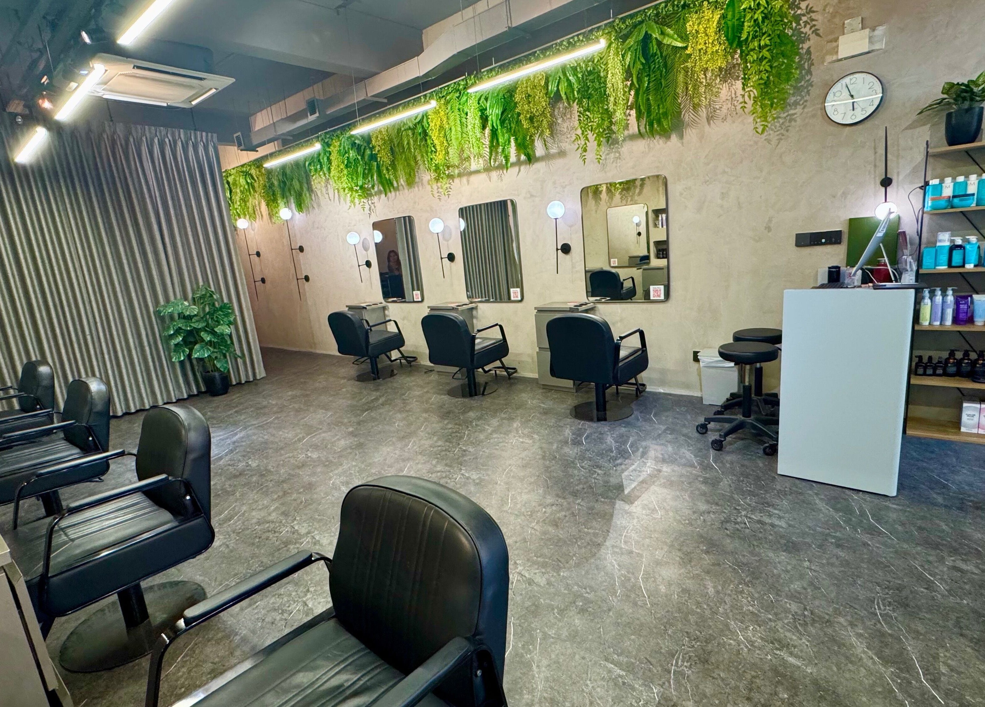 Modern hair salon interior at Blow+Bar, Singapore, SG, featuring sleek chairs and lush greenery.
