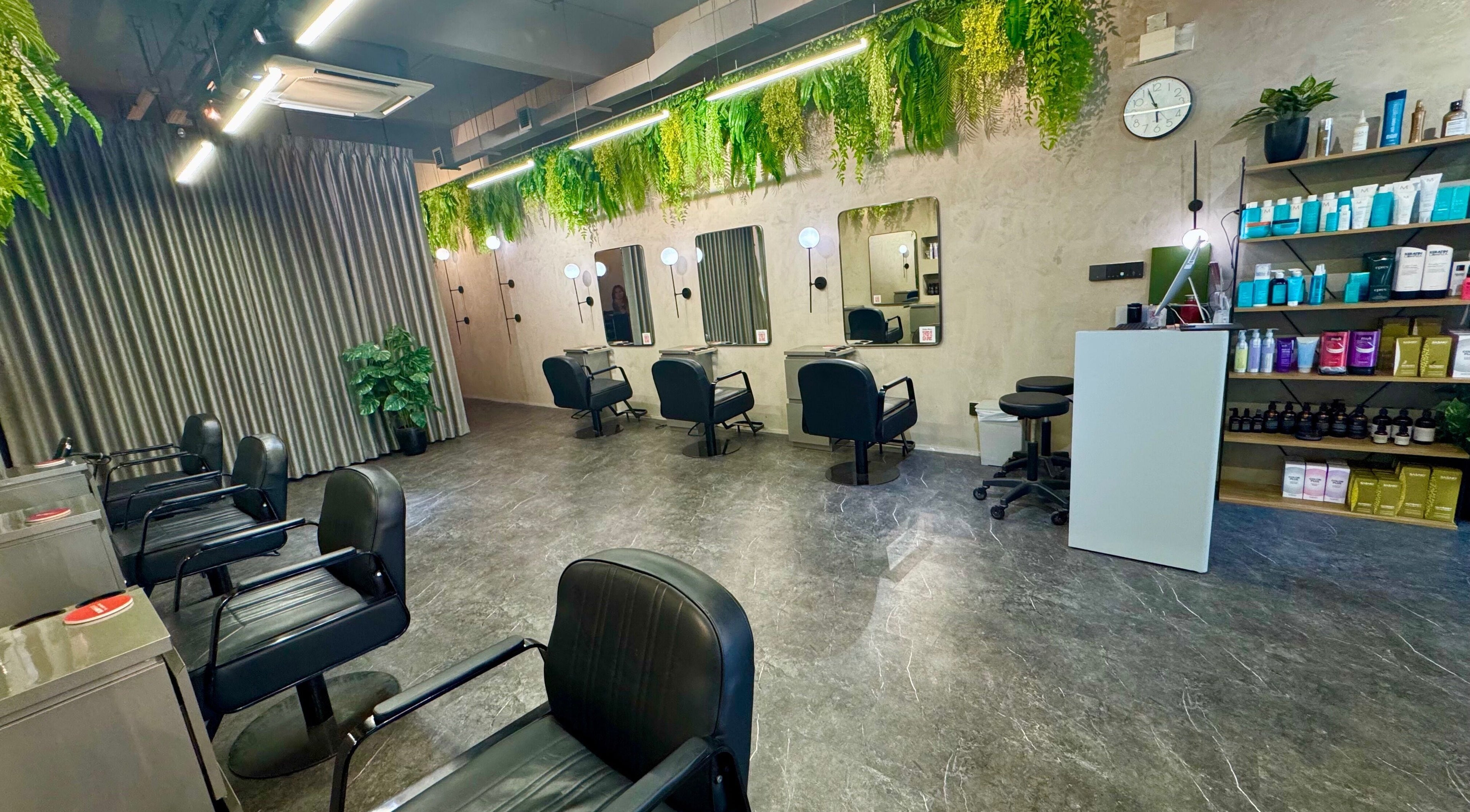 Modern hair salon interior at Blow+Bar, Singapore, SG, featuring sleek chairs and lush greenery.