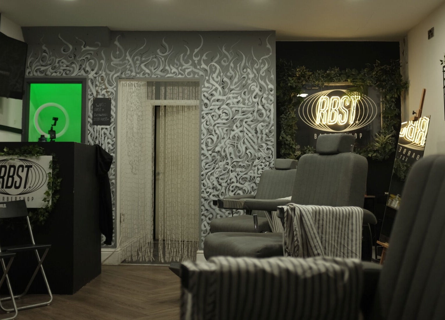 Stylish interior of RBST+ Barber Shop in Horwich, England, GB with modern chairs and artistic wall designs.