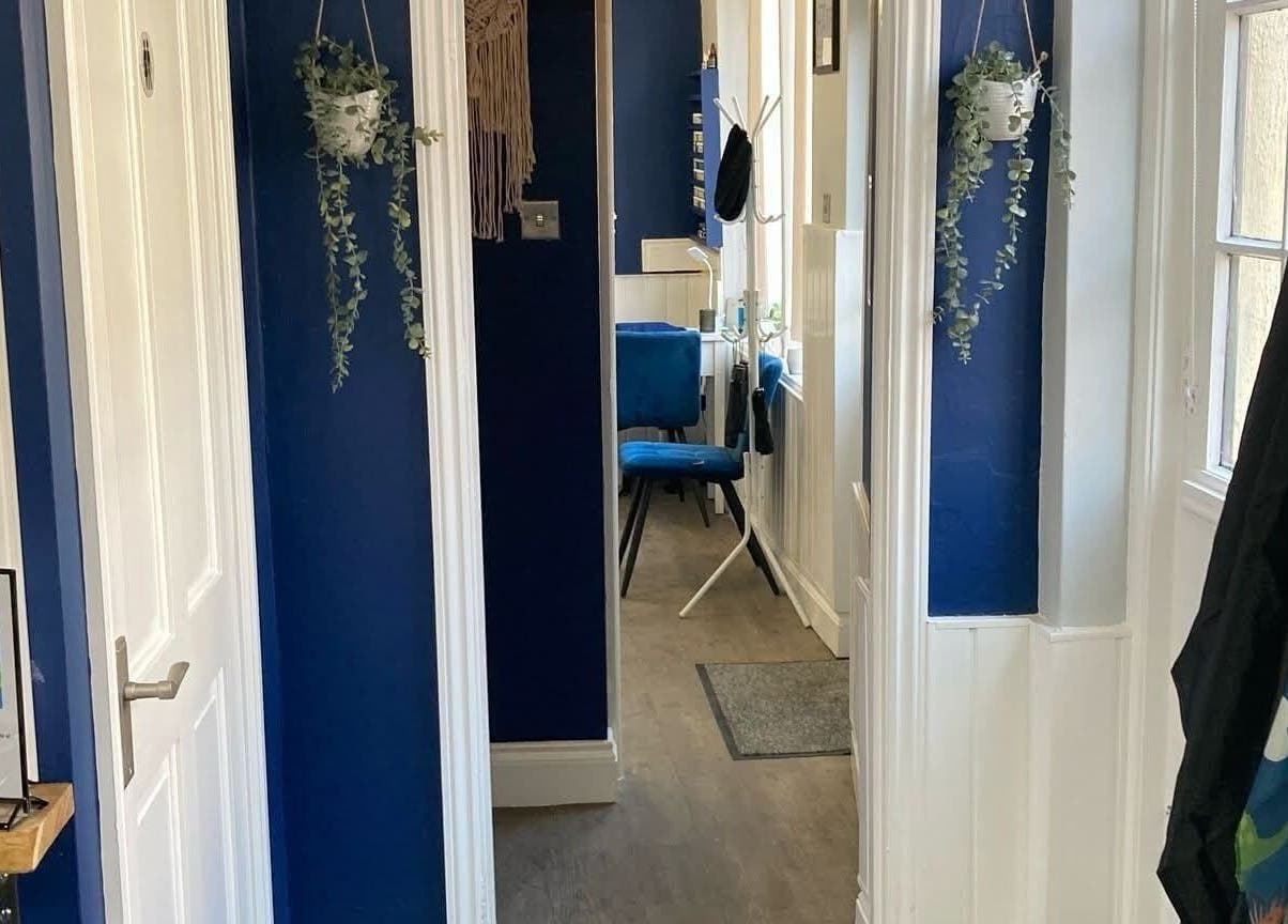 Chic hallway at Blended Hair Studio, Dereham, England, GB with blue walls and hanging plants.