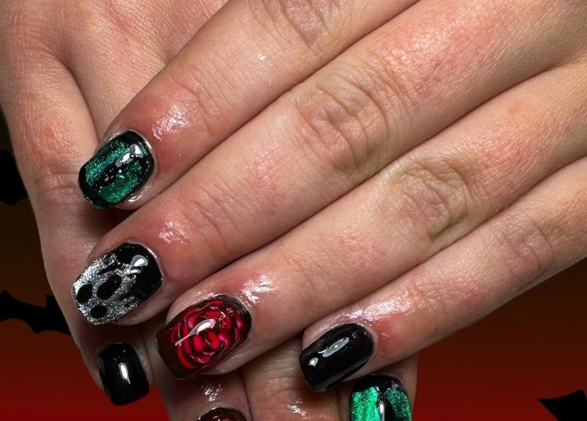 Intricate dark-themed nail art at Jazz Hands in Ripon, England, GB, showcasing silver skull and rose designs.