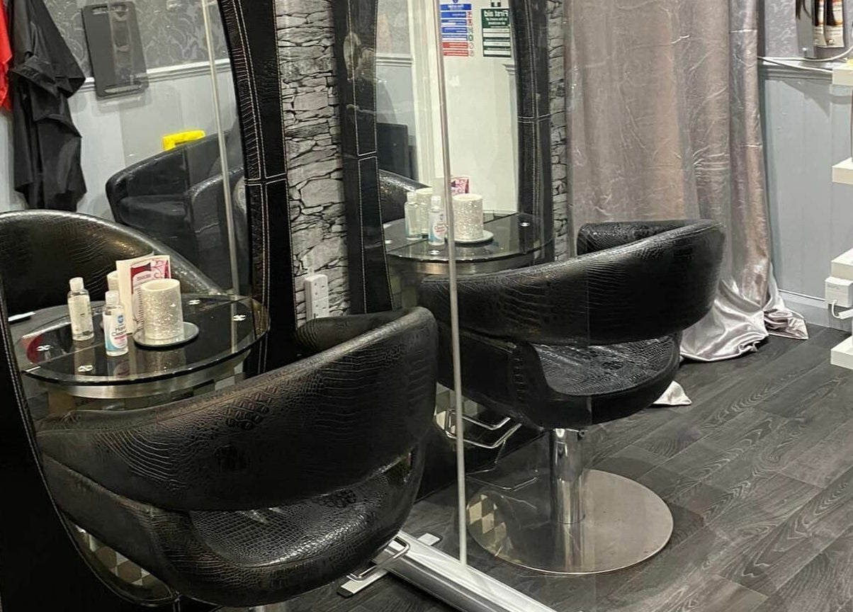 Interior of Hayley's Hands and Beauty salon in Warwick, England, featuring sleek black chairs and modern decor.