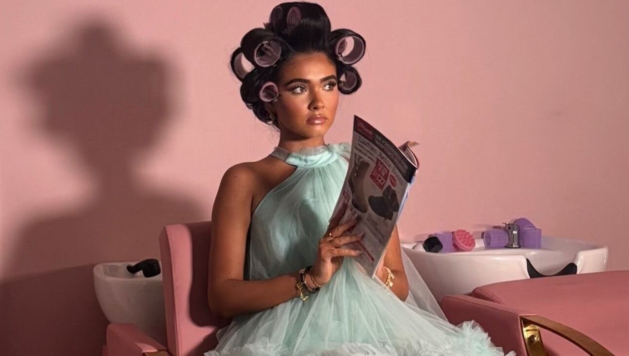 Woman with curlers reads magazine at Hair By Aimee salon, Birmingham, England, GB.