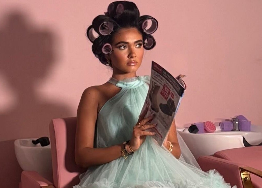 Woman with curlers reads magazine at Hair By Aimee salon, Birmingham, England, GB.