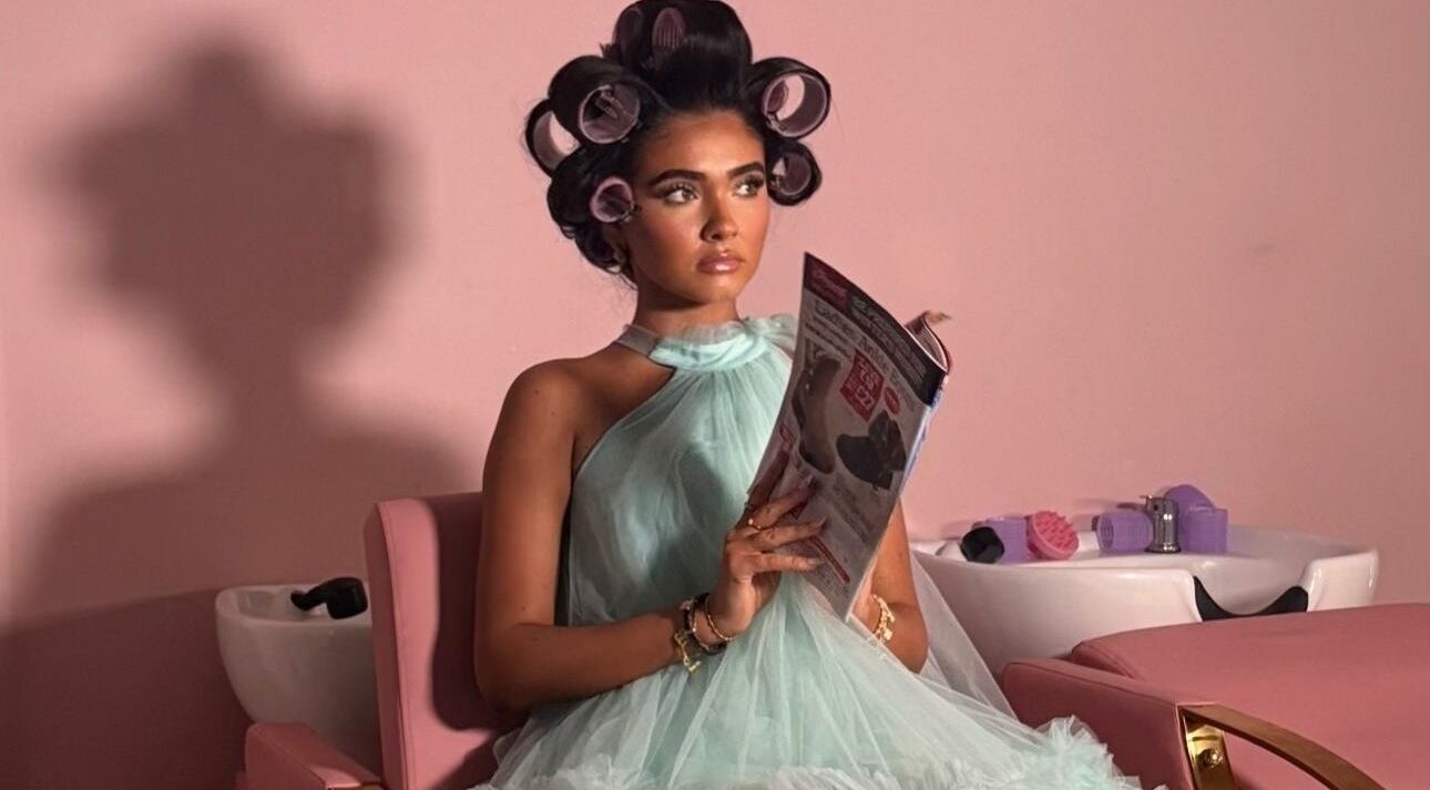 Woman with curlers reads magazine at Hair By Aimee salon, Birmingham, England, GB.