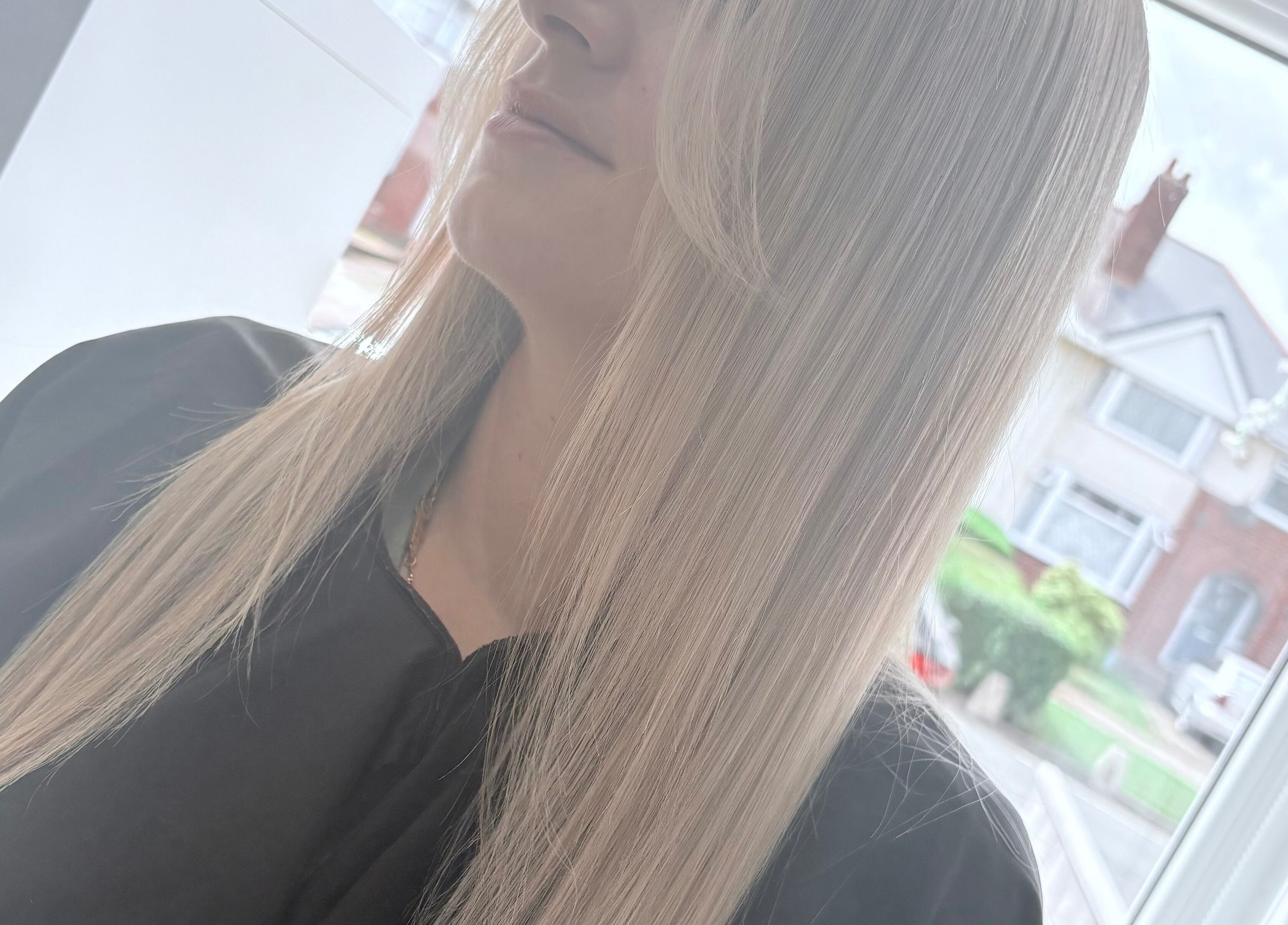 Sleek blonde hair styled at Hair By Aimee, Birmingham, England, GB. Natural light highlights the smooth texture.