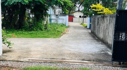 Entrance to Salon Udani in Wattala, Western Province, LK, framed by lush greenery and a stone path.