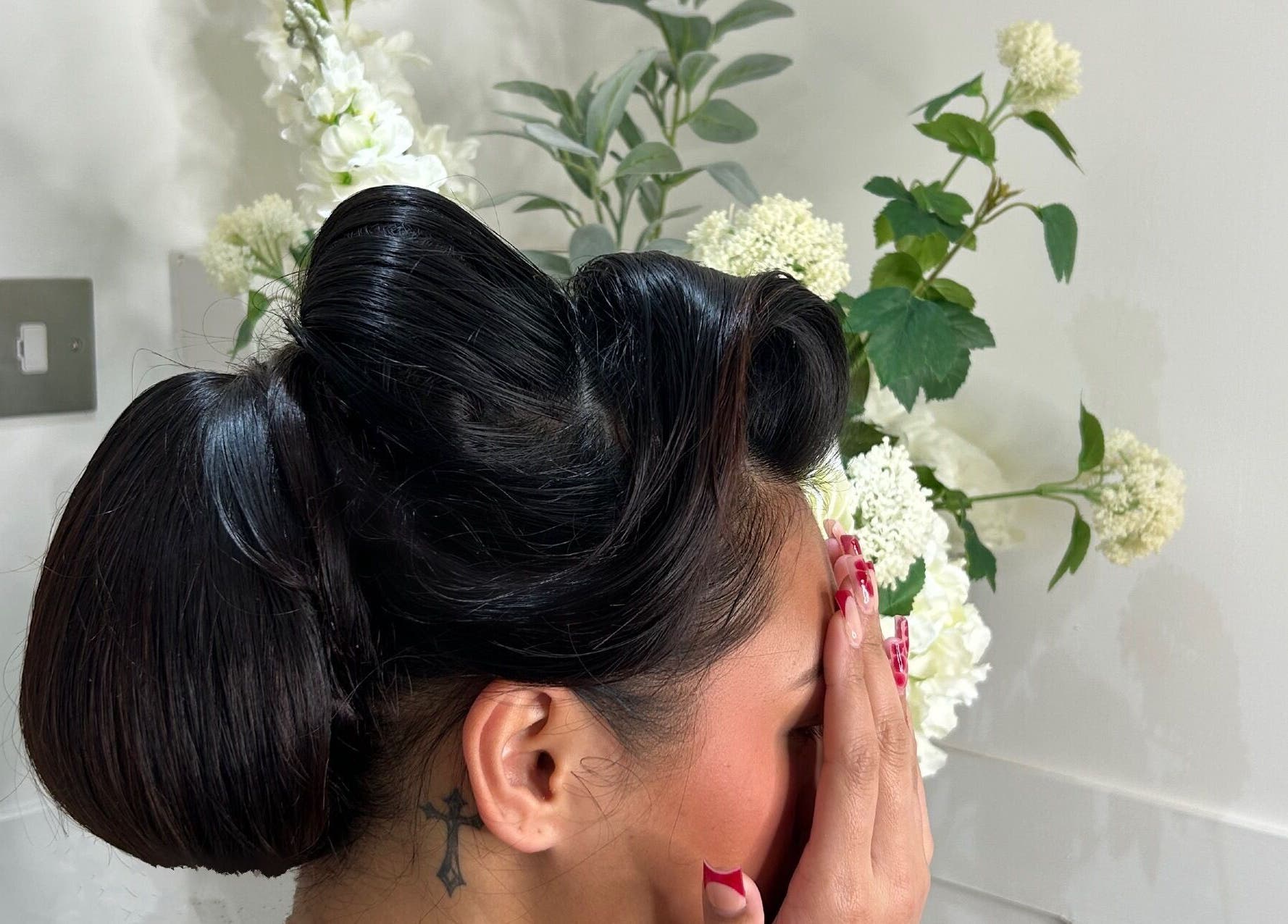 Stylish updo hairstyle at Dolled Up salon, Bournemouth, England, GB, with floral background.