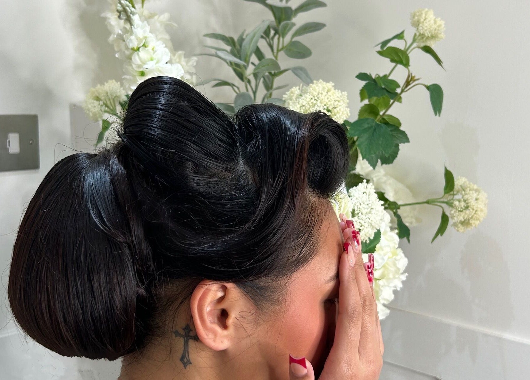 Stylish updo hairstyle at Dolled Up salon, Bournemouth, England, GB, with floral background.