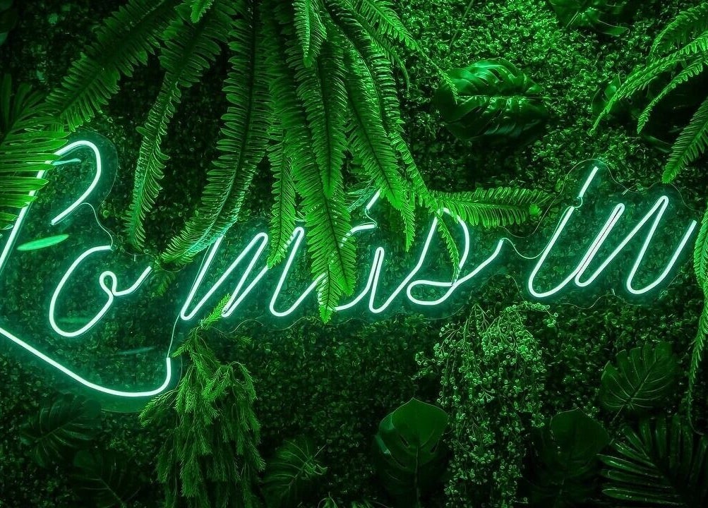 Neón verde de 'Lo Más In' en una pared vegetal en Lo Más In - El Bercial, Getafe, Comunidad De Madrid, ES.